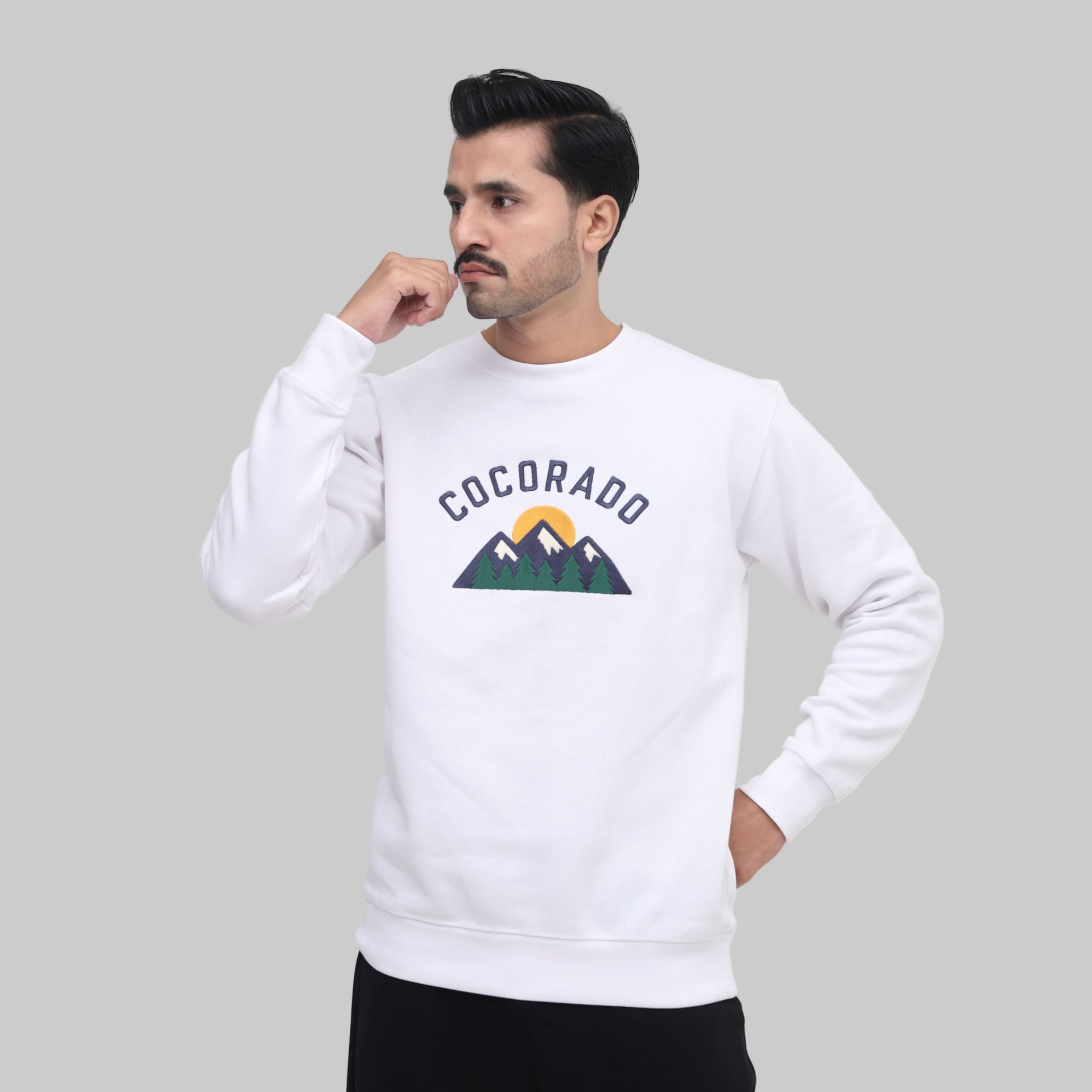 Man wearing a white sweatshirt with 'Cocorado' logo on a plain background